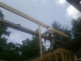 Carpenter setting a ridge beam over a new addition frame — Ice Dam Removal by Roofing Brothers in Creighton